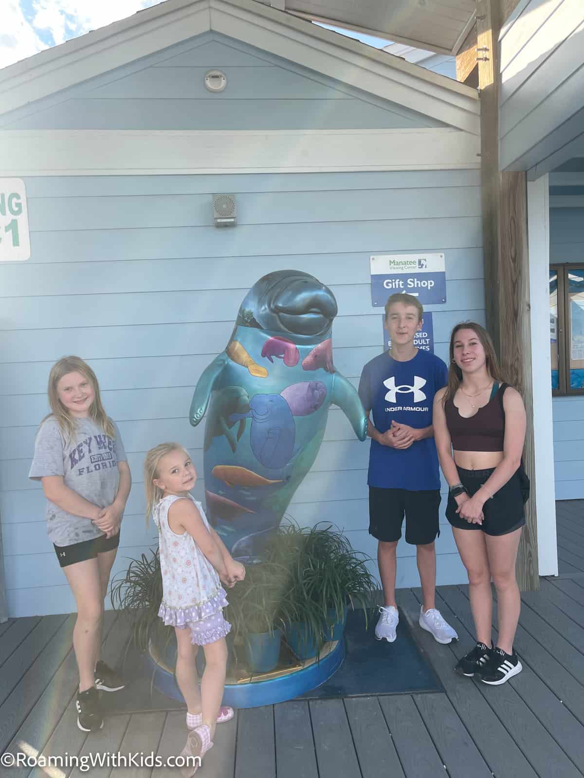 Kids standing with a manatee statue at the Manatee Viewing Center and Education Center at Tampa Electric in Tampa Florida
