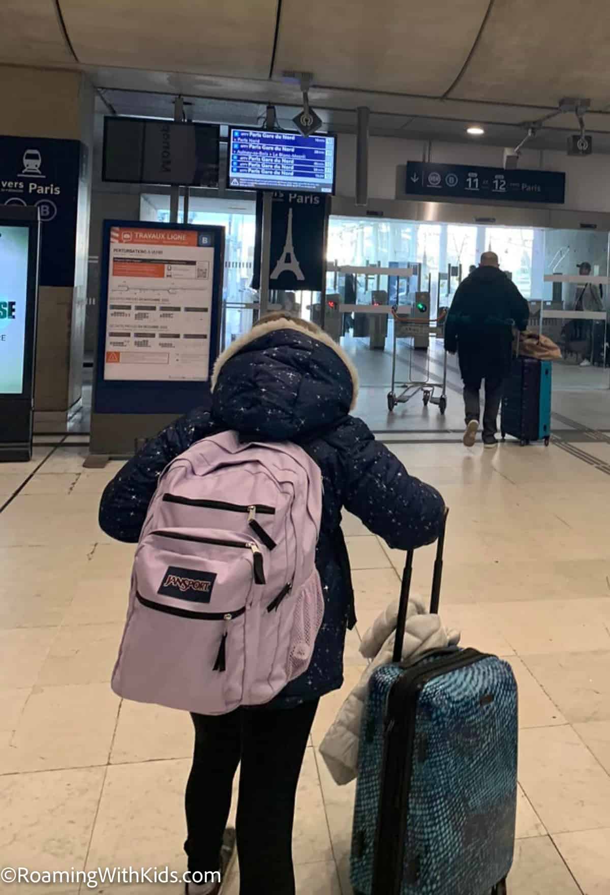 child carrying a carry-on suitcase and a carry-on backpack