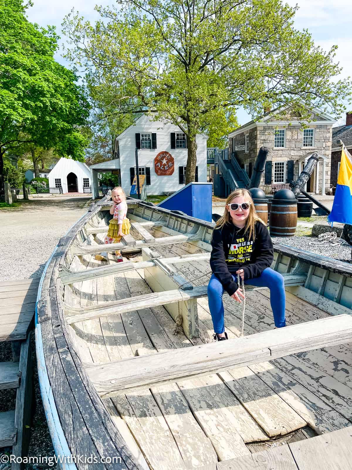 2 kids sitting in a boat while visiting Mystic Seaport Museum with kids